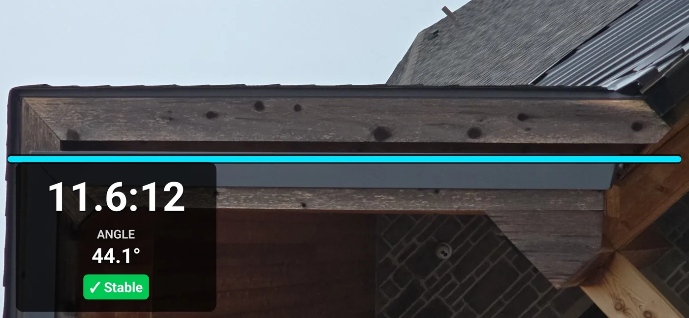 Pitch Please Camera Mode measuring a steep roofline at the eave, reading 11.6:12 pitch at a 44.1 degree angle with the alignment line matched to the gutter and a stable indicator